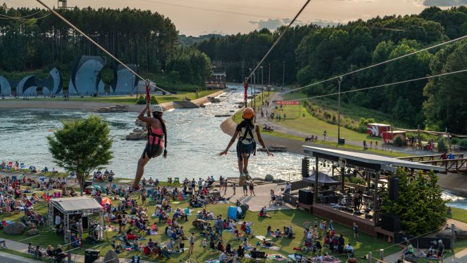 Two women zip-lining over the grounds at the U.S. National Whitewater Center in Charlotte, NC.
