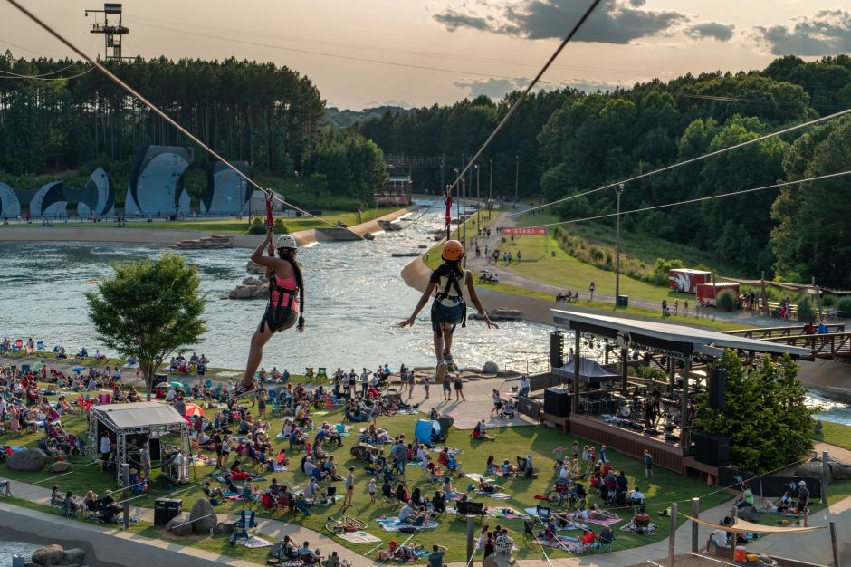 Two women zip-lining over the grounds at the U.S. National Whitewater Center in Charlotte, NC.