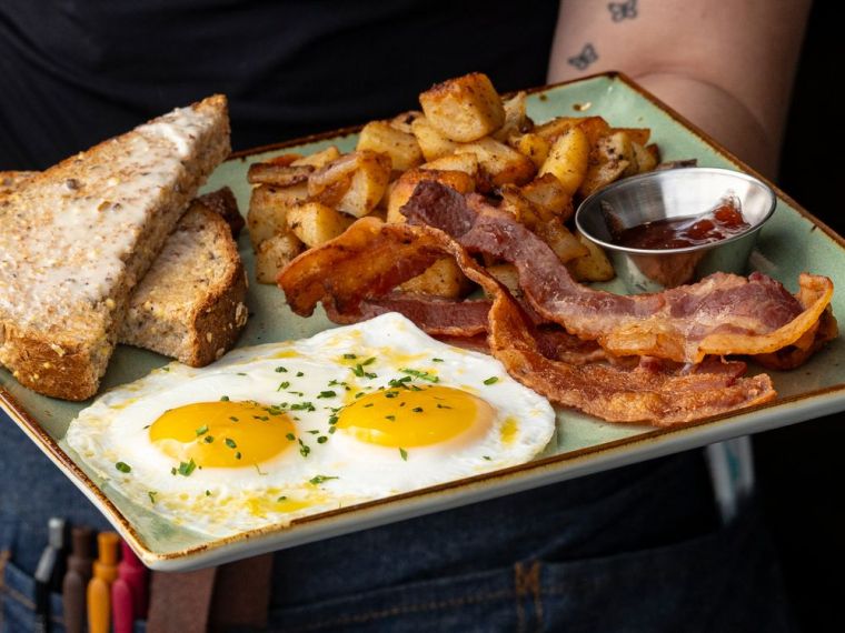 Breakfast with eggs over easy, homestyle potatoes, bacon, and toast with berry extract from First Watch restaurant in Charlotte, NC